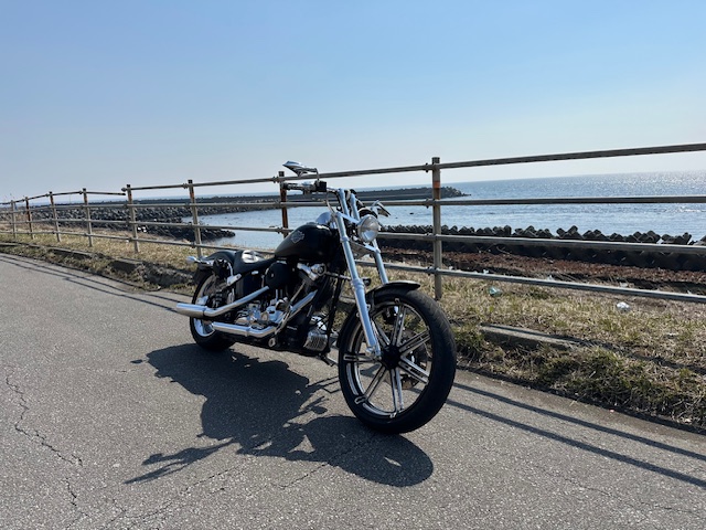 北海道の海岸道路と津軽海峡を背景にしたハーレーソフテイルカスタムのツーリング風景