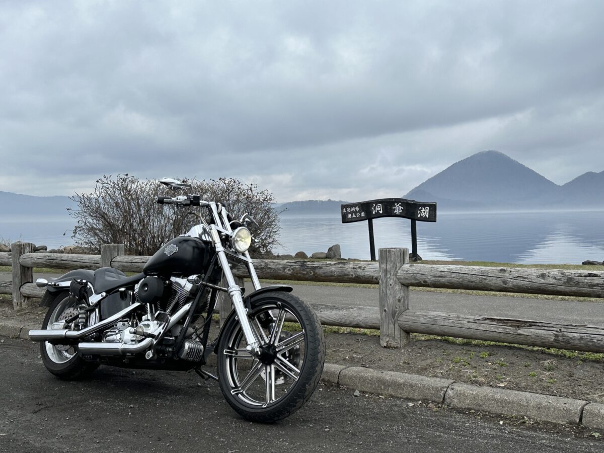 北海道・洞爺湖の湖畔に停めたハーレーダビッドソンFXSTソフテイルのツーリング風景(曇天の静かな湖と山を背景)